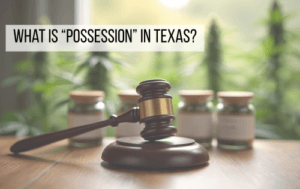Gavel on a desk in front of cannabis jars with text reading “What is Possession in Texas?”