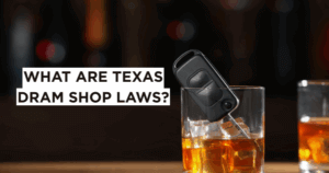 Glass of whiskey with car key inside on a bar counter, symbolizing the dangers of drunk driving and Texas dram shop liability for overserving alcohol.