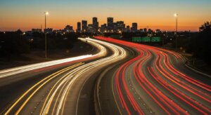 Long exposure shot of trucks moving rapidly on a multi-lane Texas highway at dusk, emphasizing high traffic volume.